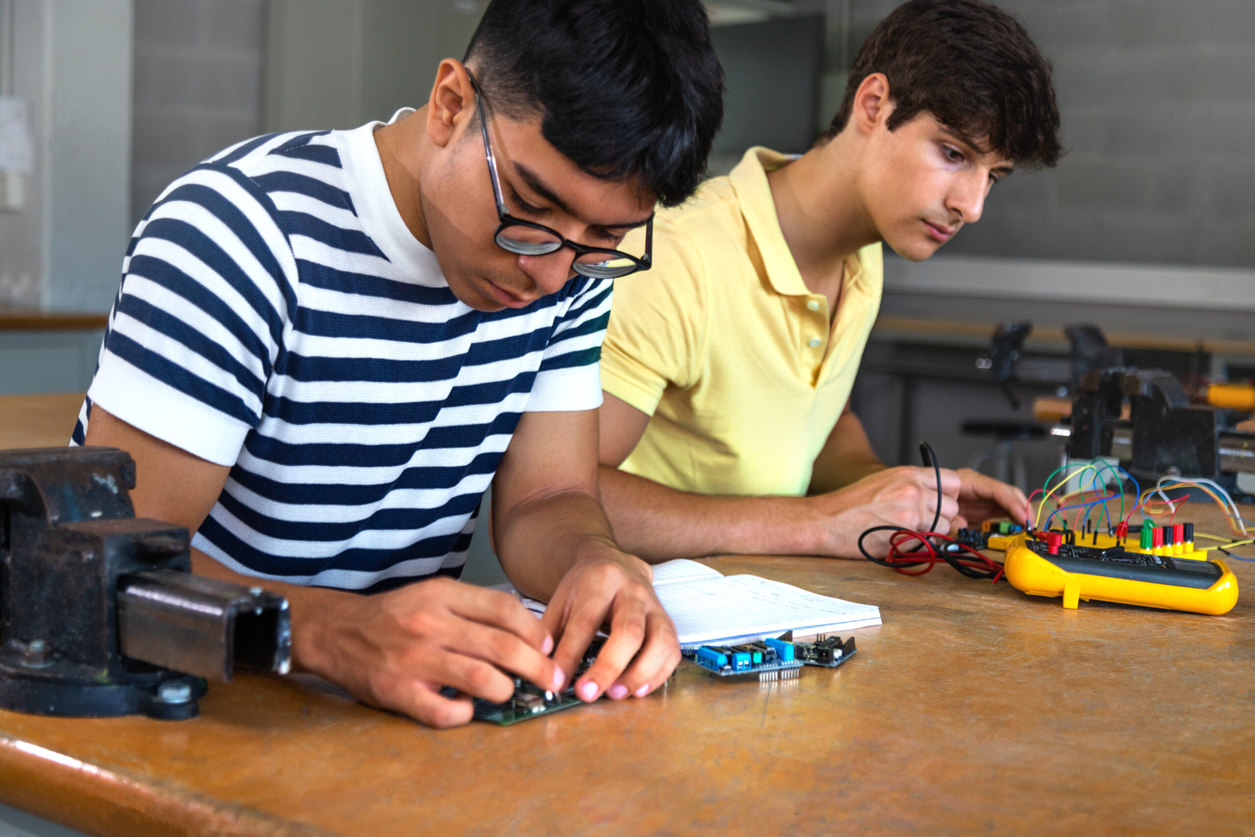 Male multiracial teen high school students working together on a project in electronics class. Education concept. Cooperation concept.